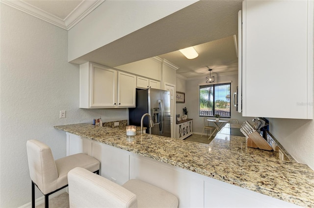 kitchen featuring white cabinetry, a breakfast bar area, ornamental molding, kitchen peninsula, and stainless steel refrigerator with ice dispenser