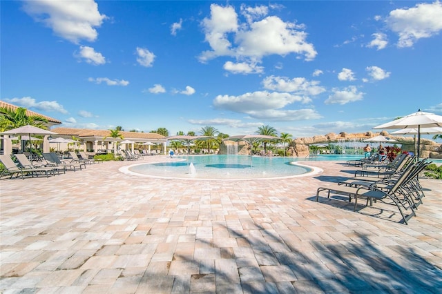 view of swimming pool with pool water feature and a patio area