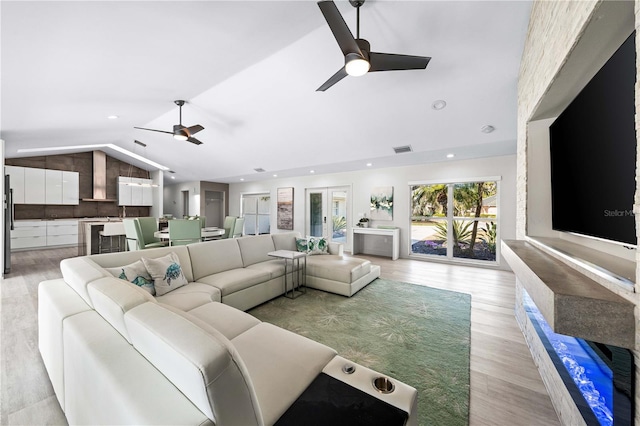 living room with ceiling fan, lofted ceiling, and light hardwood / wood-style flooring