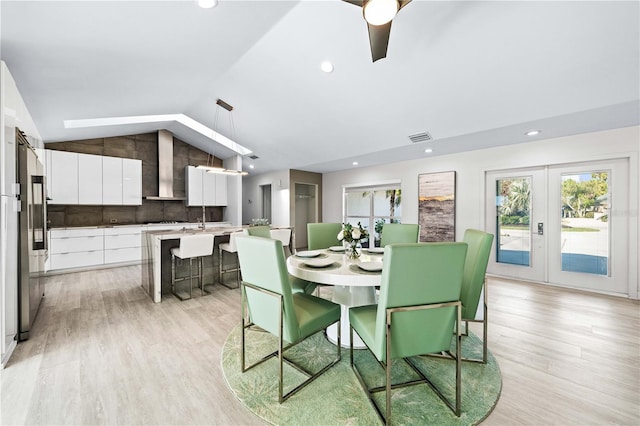 dining space with french doors, vaulted ceiling, and light wood-type flooring