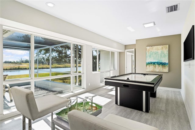 game room featuring a water view, plenty of natural light, and light hardwood / wood-style floors