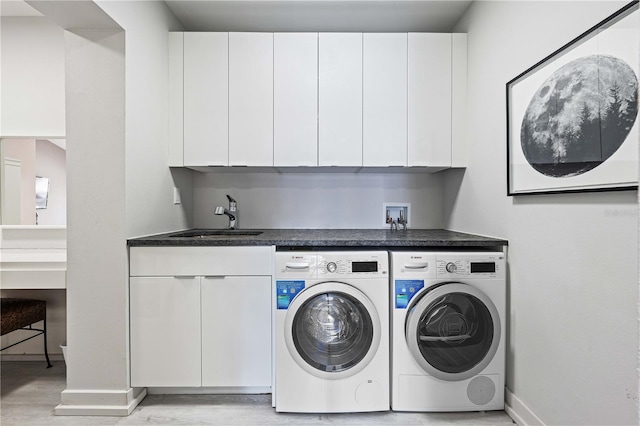 laundry area with light hardwood / wood-style floors, sink, washing machine and dryer, and cabinets