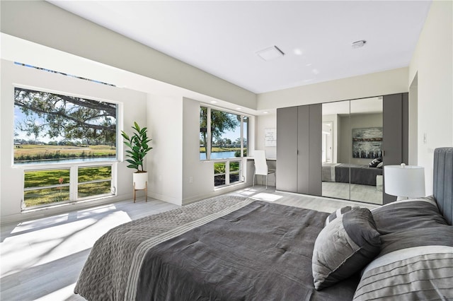 bedroom featuring light hardwood / wood-style flooring and a water view