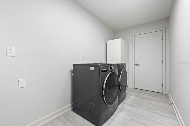 clothes washing area featuring independent washer and dryer and light hardwood / wood-style flooring