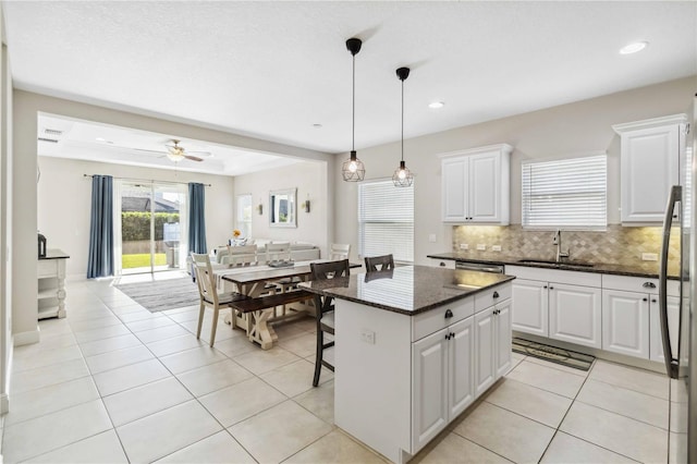 kitchen featuring a kitchen island, a breakfast bar, sink, white cabinets, and dark stone counters