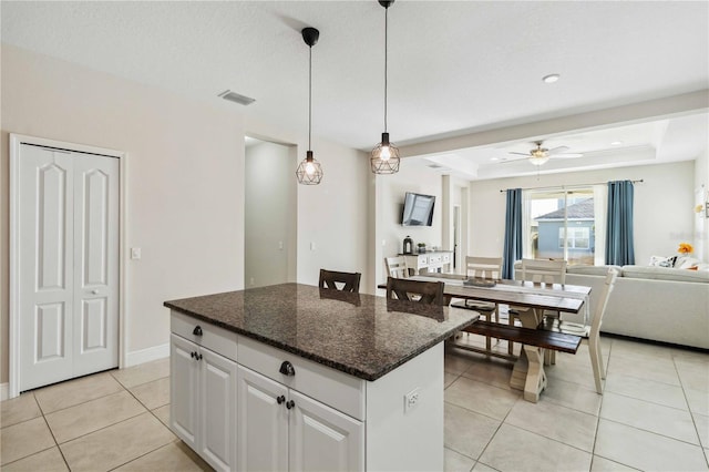 kitchen with white cabinetry, hanging light fixtures, light tile patterned floors, a tray ceiling, and a kitchen island