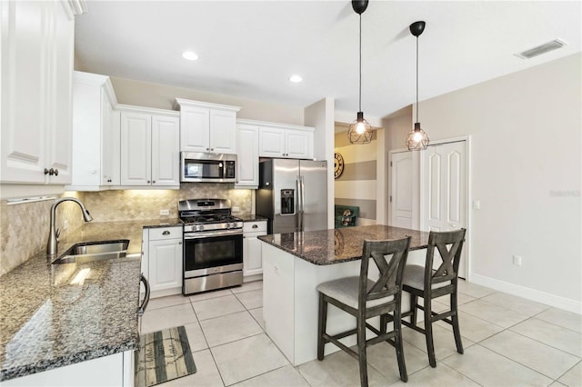 kitchen featuring white cabinetry, stainless steel appliances, sink, and a kitchen island