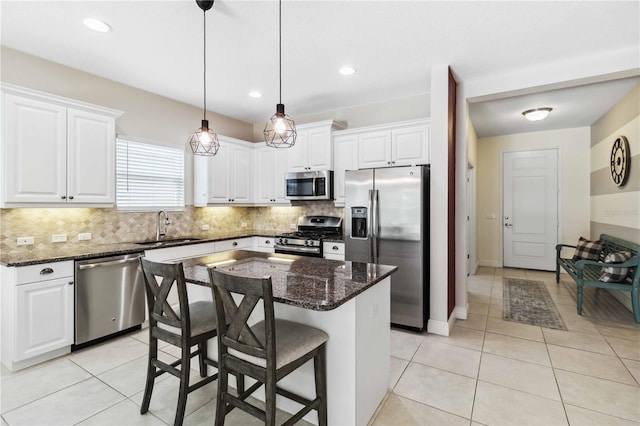 kitchen with white cabinetry, tasteful backsplash, a center island, dark stone countertops, and stainless steel appliances