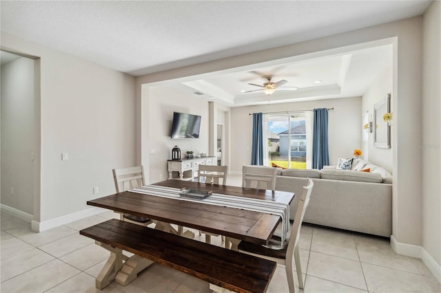 tiled dining space featuring a tray ceiling and ceiling fan