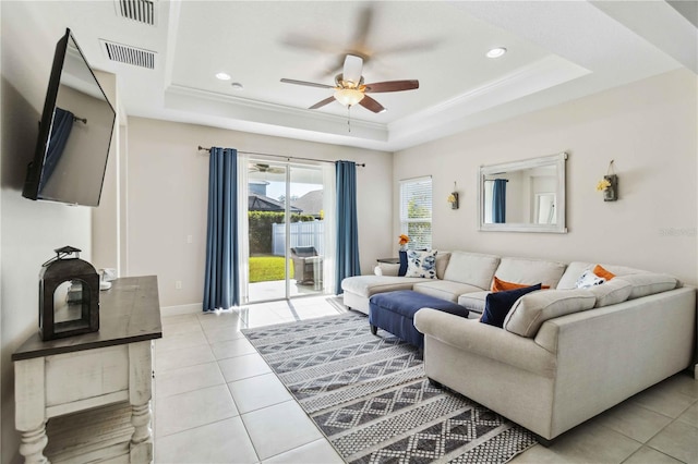 living room with ornamental molding, a tray ceiling, and light tile patterned floors