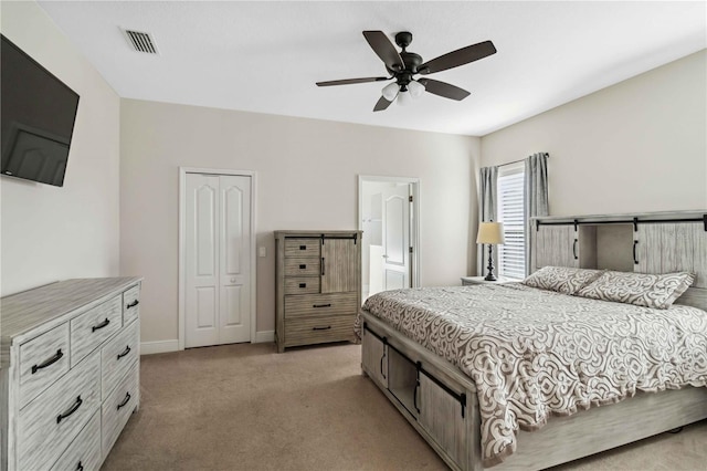 carpeted bedroom with ensuite bathroom, ceiling fan, and a closet