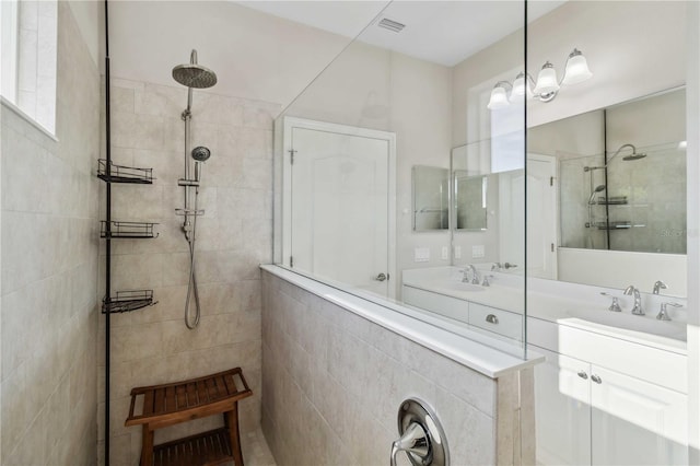 bathroom featuring tiled shower and vanity