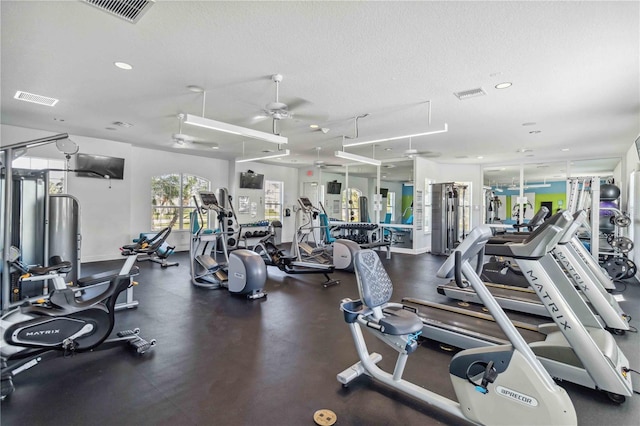 gym featuring ceiling fan and a textured ceiling