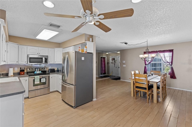 kitchen featuring white cabinetry, a textured ceiling, hanging light fixtures, light hardwood / wood-style flooring, and appliances with stainless steel finishes