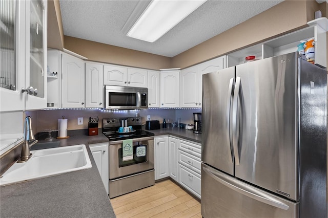 kitchen with light wood-type flooring, stainless steel appliances, sink, and white cabinets