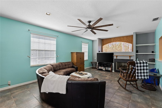 living room featuring ceiling fan and a textured ceiling