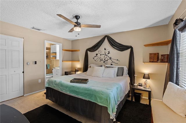 bedroom featuring ceiling fan, connected bathroom, light colored carpet, and a textured ceiling