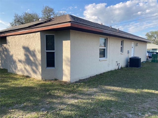 view of side of property featuring central AC and a lawn