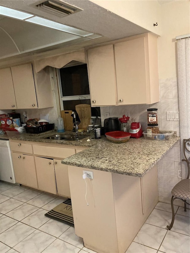 kitchen with sink, dishwasher, cream cabinets, light stone countertops, and kitchen peninsula