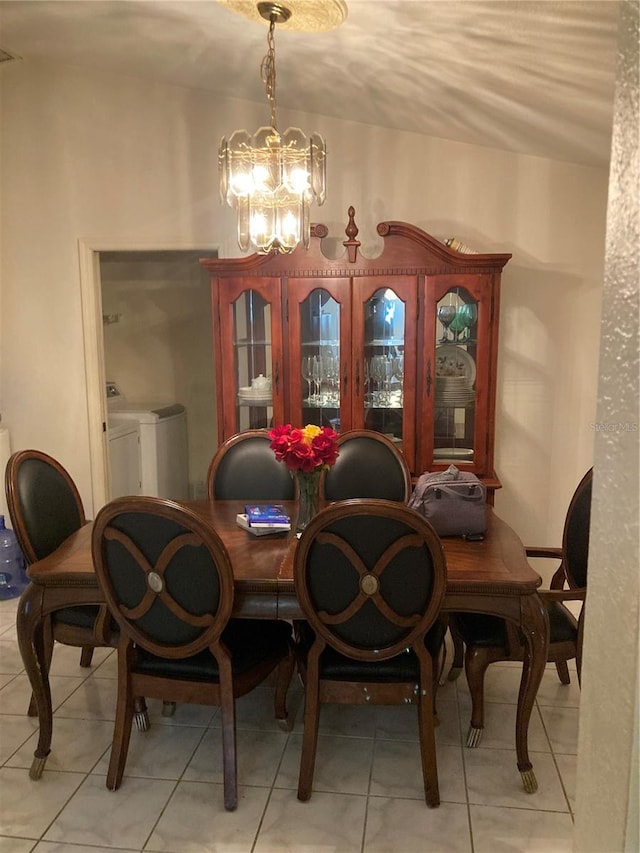 tiled dining room featuring a notable chandelier and washer and clothes dryer