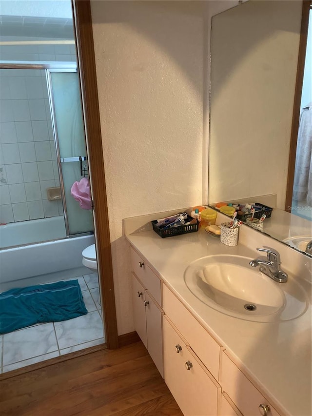 full bathroom featuring vanity, combined bath / shower with glass door, wood-type flooring, and toilet