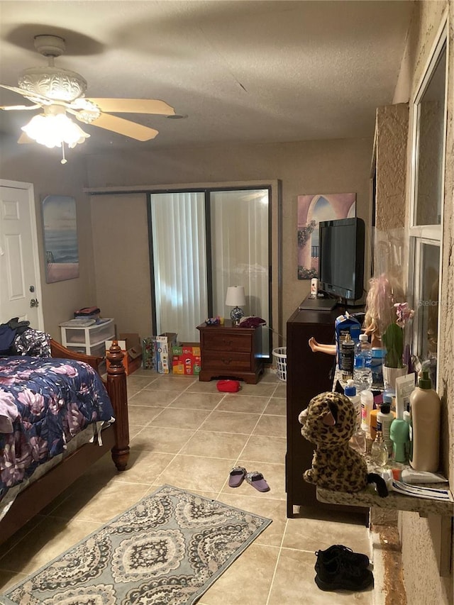 tiled bedroom with ceiling fan and a textured ceiling