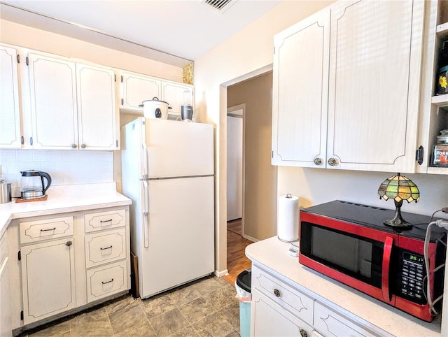 kitchen featuring light countertops, freestanding refrigerator, and white cabinetry