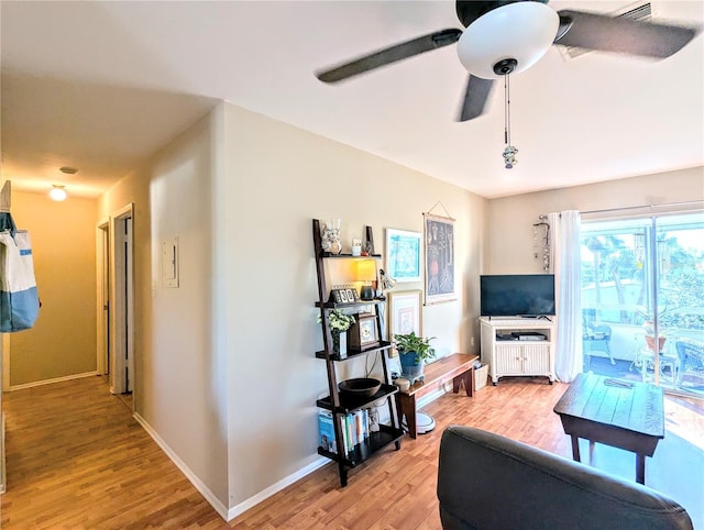 living area with light wood-type flooring, baseboards, and a ceiling fan