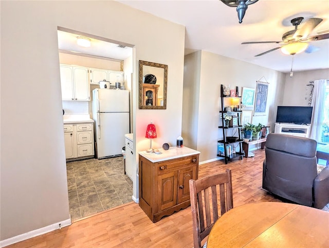 dining space with visible vents, light wood-type flooring, a ceiling fan, and baseboards