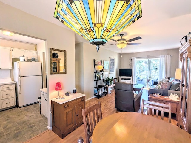 dining space with ceiling fan, light wood-style floors, and baseboards