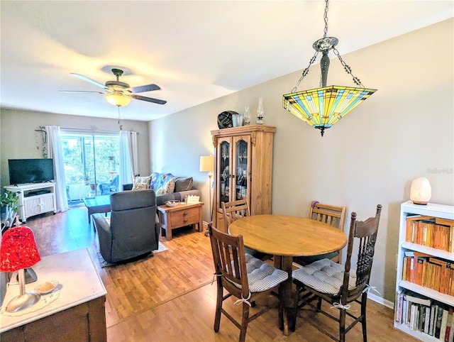 dining area with wood finished floors, a ceiling fan, and baseboards