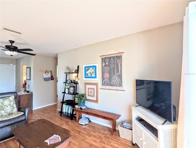 living room featuring a ceiling fan, light wood-type flooring, visible vents, and baseboards