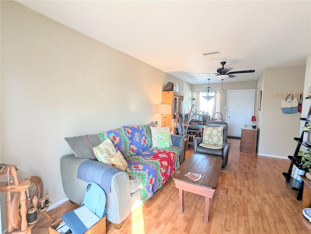 living area with light wood finished floors, a ceiling fan, visible vents, and baseboards