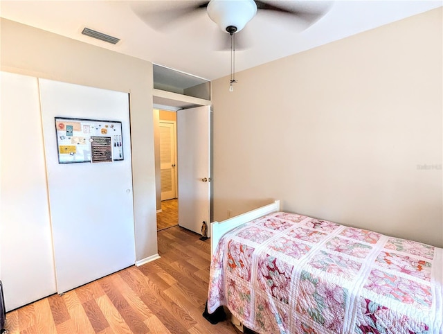 bedroom featuring light wood-style floors, visible vents, and a ceiling fan