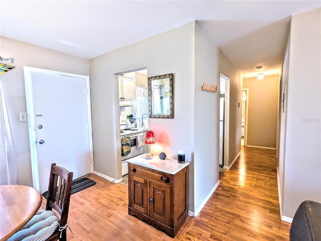 hall featuring light wood finished floors and baseboards