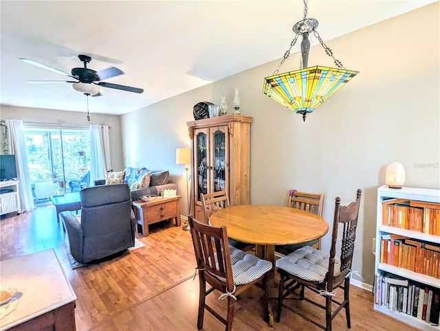 dining space with baseboards, a ceiling fan, and wood finished floors