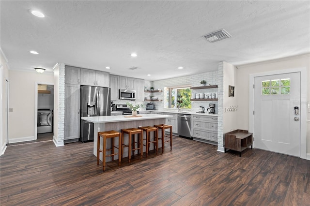 kitchen with dark hardwood / wood-style floors, stainless steel appliances, a center island, and a kitchen bar