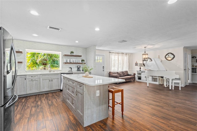 kitchen featuring stainless steel refrigerator with ice dispenser, a breakfast bar, dark wood-type flooring, and a kitchen island