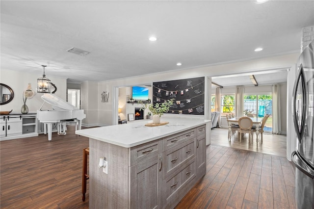 kitchen featuring stainless steel refrigerator, dark hardwood / wood-style floors, hanging light fixtures, and a kitchen island