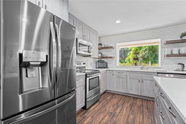 kitchen with sink, dark wood-type flooring, appliances with stainless steel finishes, gray cabinetry, and decorative backsplash