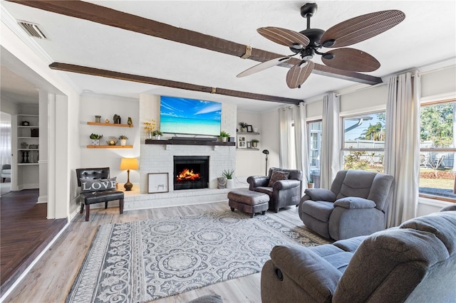 living room with beamed ceiling, ornamental molding, a fireplace, and wood-type flooring