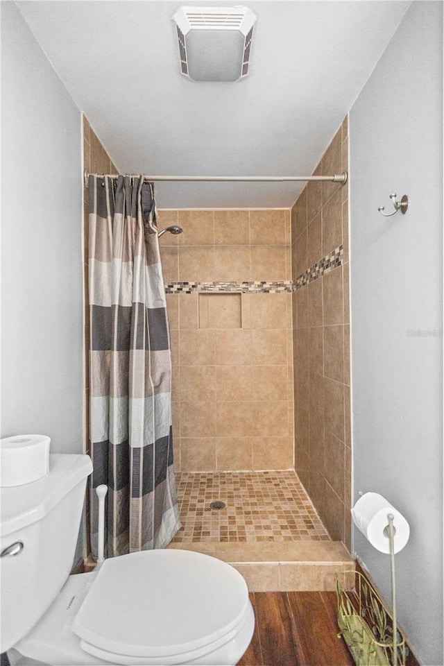 bathroom with a shower with curtain, toilet, and hardwood / wood-style flooring