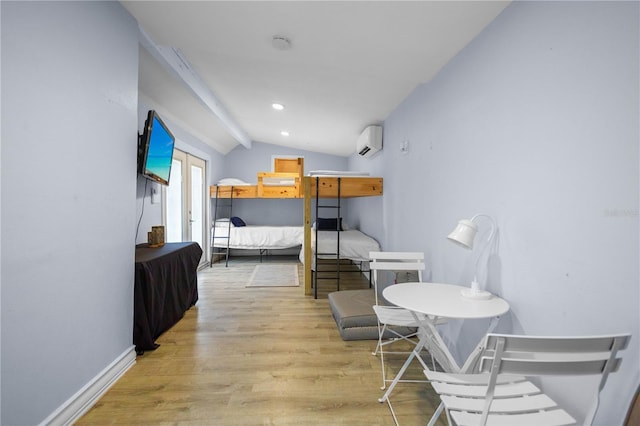 bedroom with a wall mounted air conditioner, light hardwood / wood-style floors, and vaulted ceiling