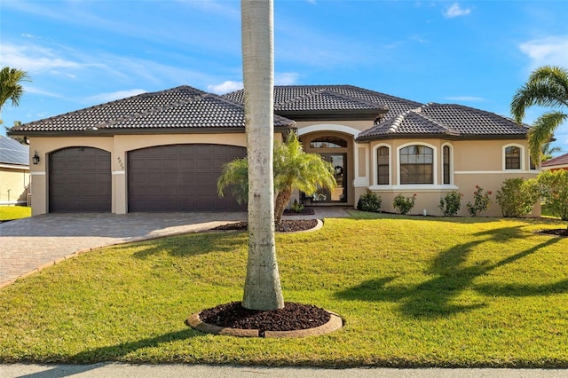 mediterranean / spanish home featuring a garage and a front yard