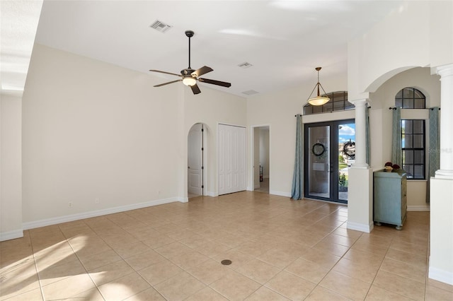 unfurnished living room with light tile patterned floors, a high ceiling, ceiling fan, and ornate columns