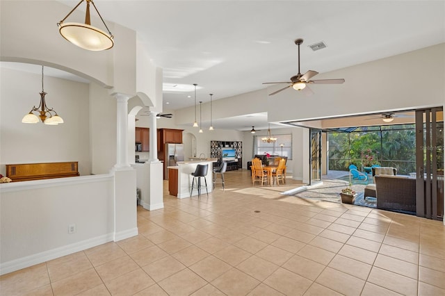 unfurnished living room with ceiling fan with notable chandelier, light tile patterned flooring, and decorative columns