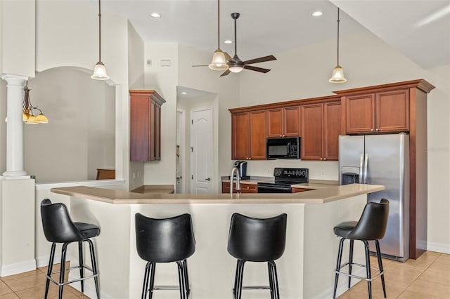 kitchen featuring light tile patterned flooring, a kitchen bar, pendant lighting, decorative columns, and black appliances