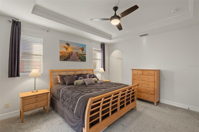 bedroom featuring light colored carpet, ornamental molding, a raised ceiling, and ceiling fan