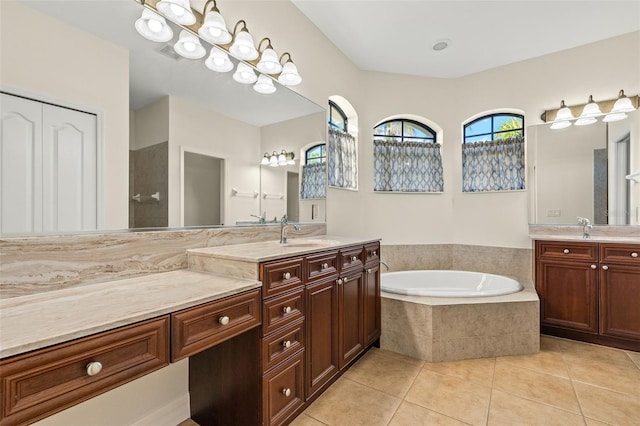 bathroom featuring vanity, a relaxing tiled tub, and tile patterned floors