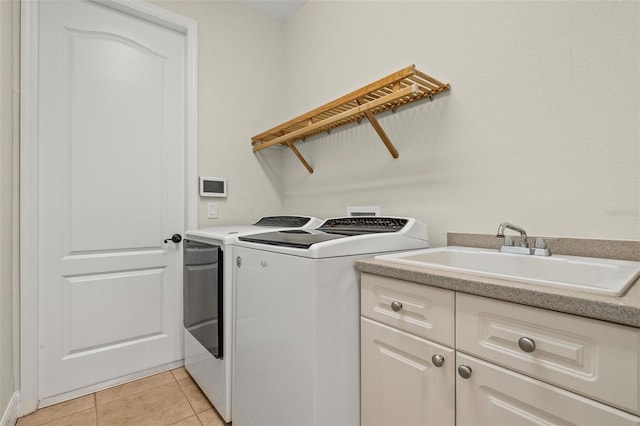 clothes washing area featuring cabinets, sink, washer and dryer, and light tile patterned floors